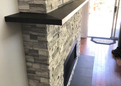 Double Sided Ledgestone Tile Fireplace with Charred Wood Mantle and See-Through Gas Insert with Heat Shift Vent Side 1 Corner Detail - Broadmead