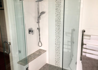 Corner Shower with Stone Bench Top and Vertical Mosaic Tile Band - Feltham